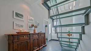 Een modern interieur met een houten kast, ingelijste foto's en een glazen trap.