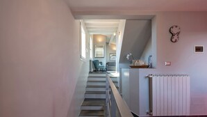 Een trap die leidt naar een woonruimte met een radiator, een klok en een stoel.