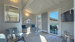 Een moderne woonkamer met een glazen salontafel, een bank, een fauteuil, een televisie en een balkon met uitzicht.