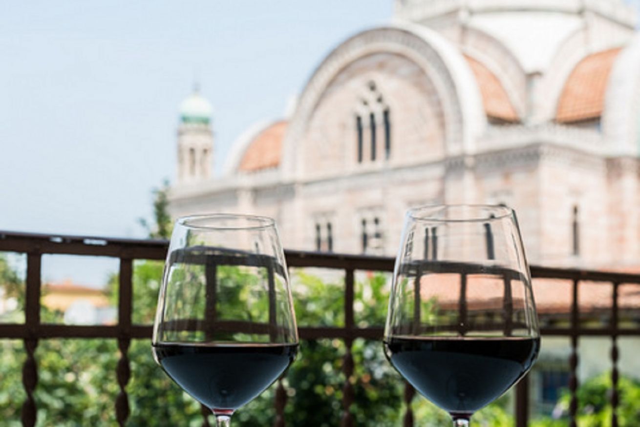 Two wine glasses on a balcony with a building in the background.