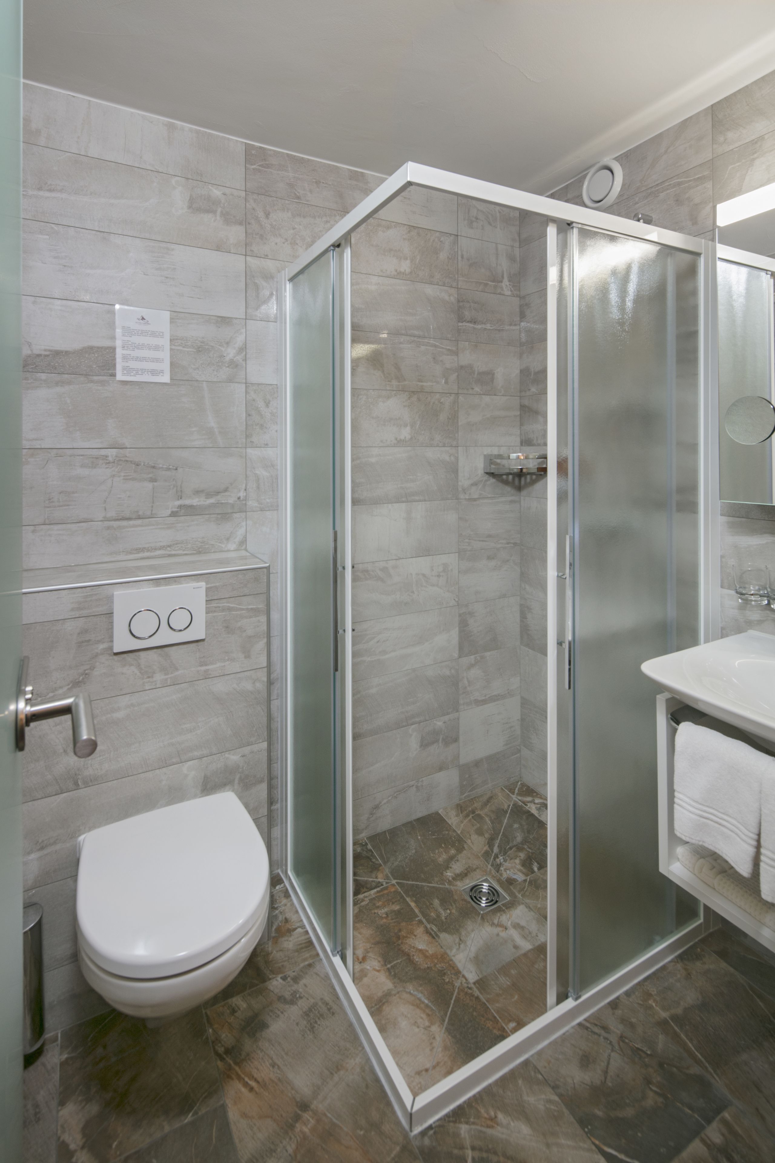 Une salle de bain moderne avec une douche à parois de verre, des toilettes blanches et un lavabo avec un miroir.