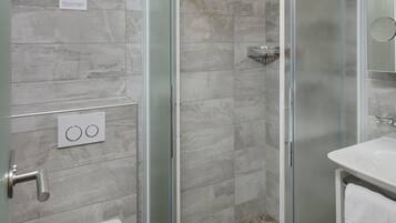 Une salle de bain moderne avec une douche à parois de verre, des toilettes blanches et un lavabo avec un miroir.