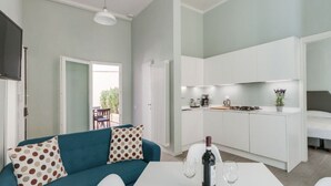 A compact living space with a kitchenette, a dining area with a table and chairs, and a sofa with patterned cushions. - Apartments Florence - Taddea Terrace (Firenze)