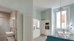 A modern kitchen with white cabinets, a built-in oven, and a dining area with a table and chairs. - Apartments Florence - Taddea Terrace (Firenze)
