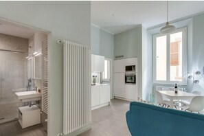 A modern kitchen with white cabinets, a built-in oven, and a dining area with a table and chairs. - Apartments Florence - Taddea Terrace (Firenze)