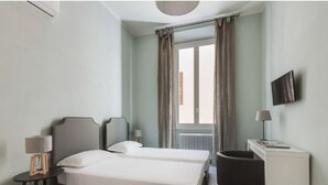 A hotel room with two beds, a desk, a chair, a TV, and a window with curtains. - Apartments Florence - Taddea Terrace (Firenze)