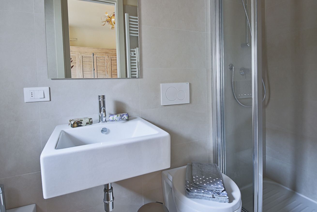 A bathroom with a white sink, a mirror, a shower, and a towel rack.