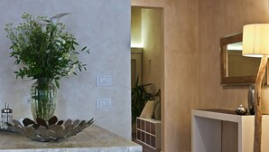 Ein Badezimmer mit einem weißen Waschbecken, einem Spiegel und einer Blumenvase auf einer Holzablage.