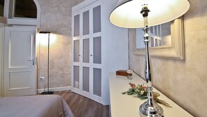 Ein Hotelzimmer mit Bett, Schreibtisch mit Lampe, Kleiderschrank und Fenster.