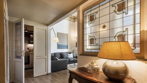 Un umbral abierto que da a una sala de estar con un sofá, una lámpara sobre una mesa y un panel decorativo en la pared.