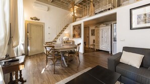Amplia sala de estar con una mesa de comedor, sofá y escalera que sube a un piso superior.