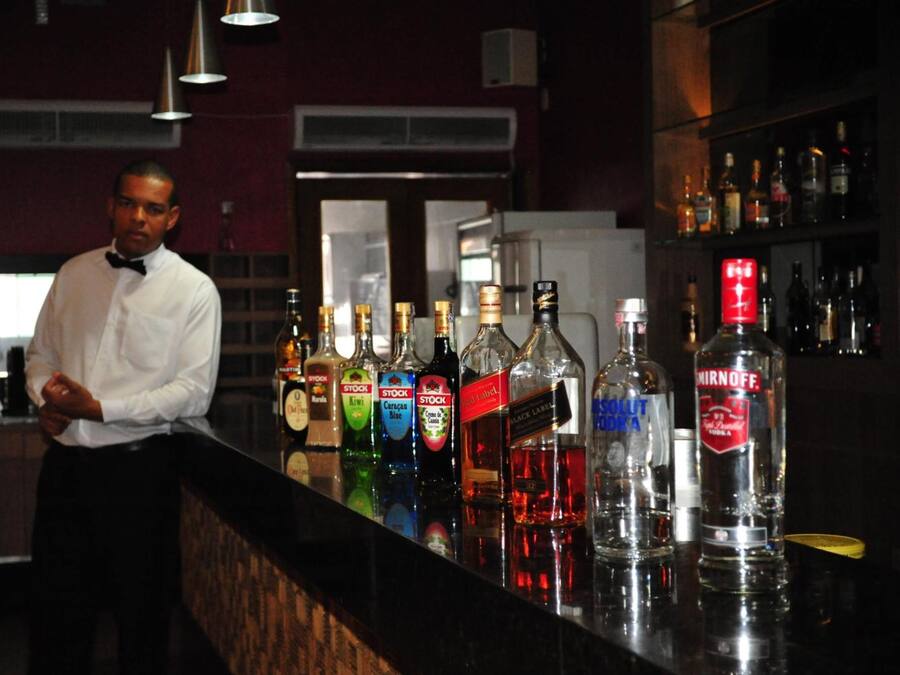 Una zona de bar con un cantinero y diferentes botellas de licor.