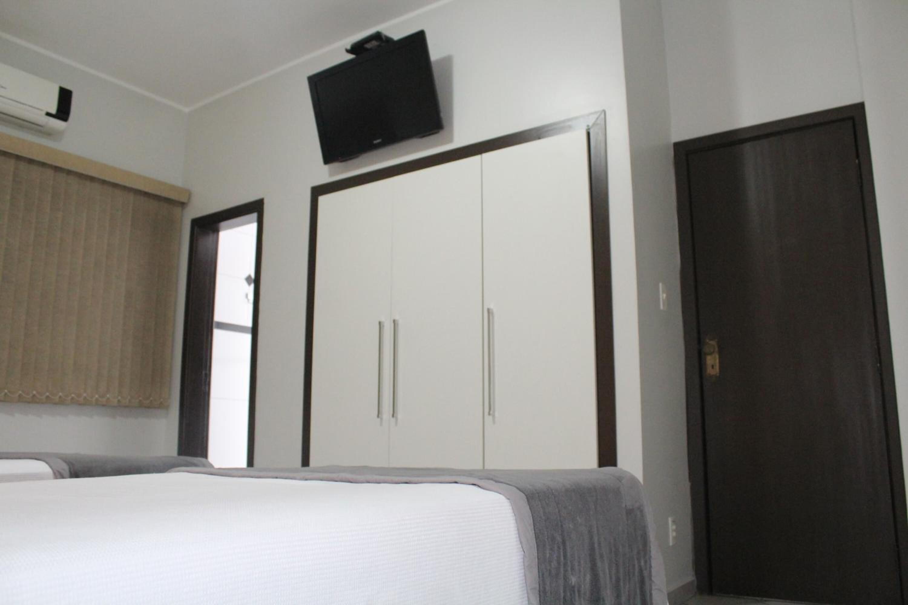 Habitació d'hotel amb llit, armari, televisió i porta.