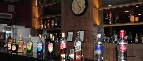 A bar area with various liquor bottles, a clock, and shelves with bottles.