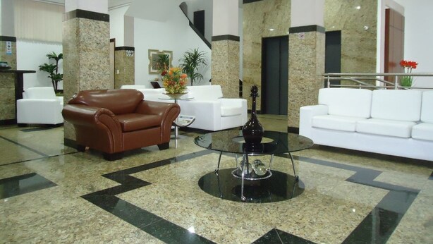 A lobby with a brown leather sofa, white armchairs, a glass coffee table, and a marble floor. - Itamaraty Hotel (Anapolis)