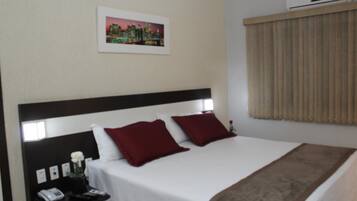 A hotel room with a large bed, a nightstand with a phone, and a picture on the wall.