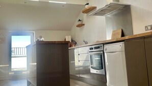 A modern kitchen with skylights, a central island, and built-in appliances. - Beach House - Penthouse 3 Bed Apartment (Southport)