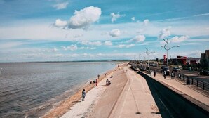 A coastal promenade with a concrete walkway, a beach, and a KFC restaurant. - Beach House - Penthouse 3 Bed Apartment (Southport)