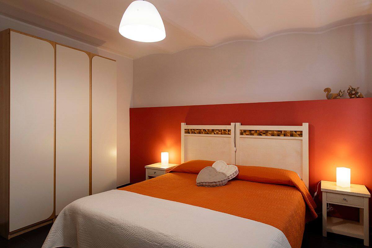 A hotel room with a bed, two bedside tables, a wardrobe, and a ceiling light.