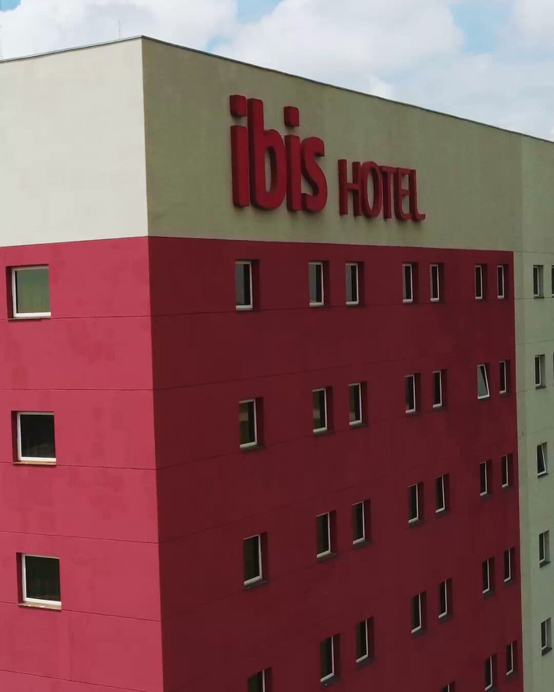 Ein Gebäude mit dem Schild 'ibis hotel', das ein Hotel kennzeichnet.
