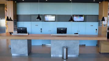 A reception desk with two computers, a trash bin, and a security camera.