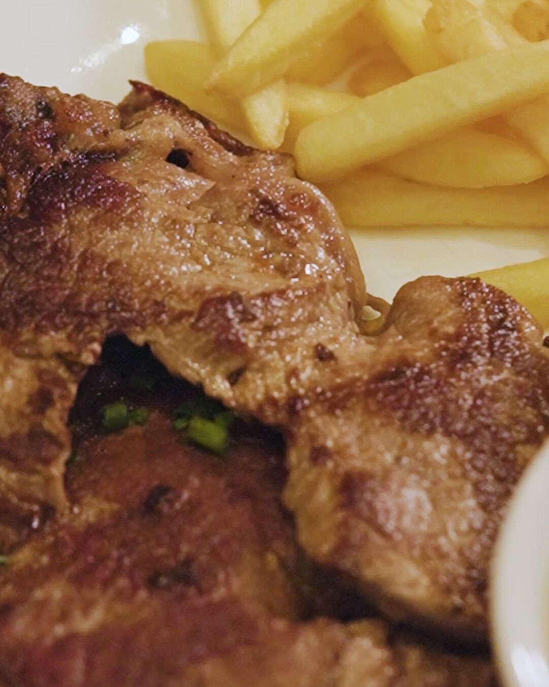 Un plato de carne a la parrilla y papas fritas.