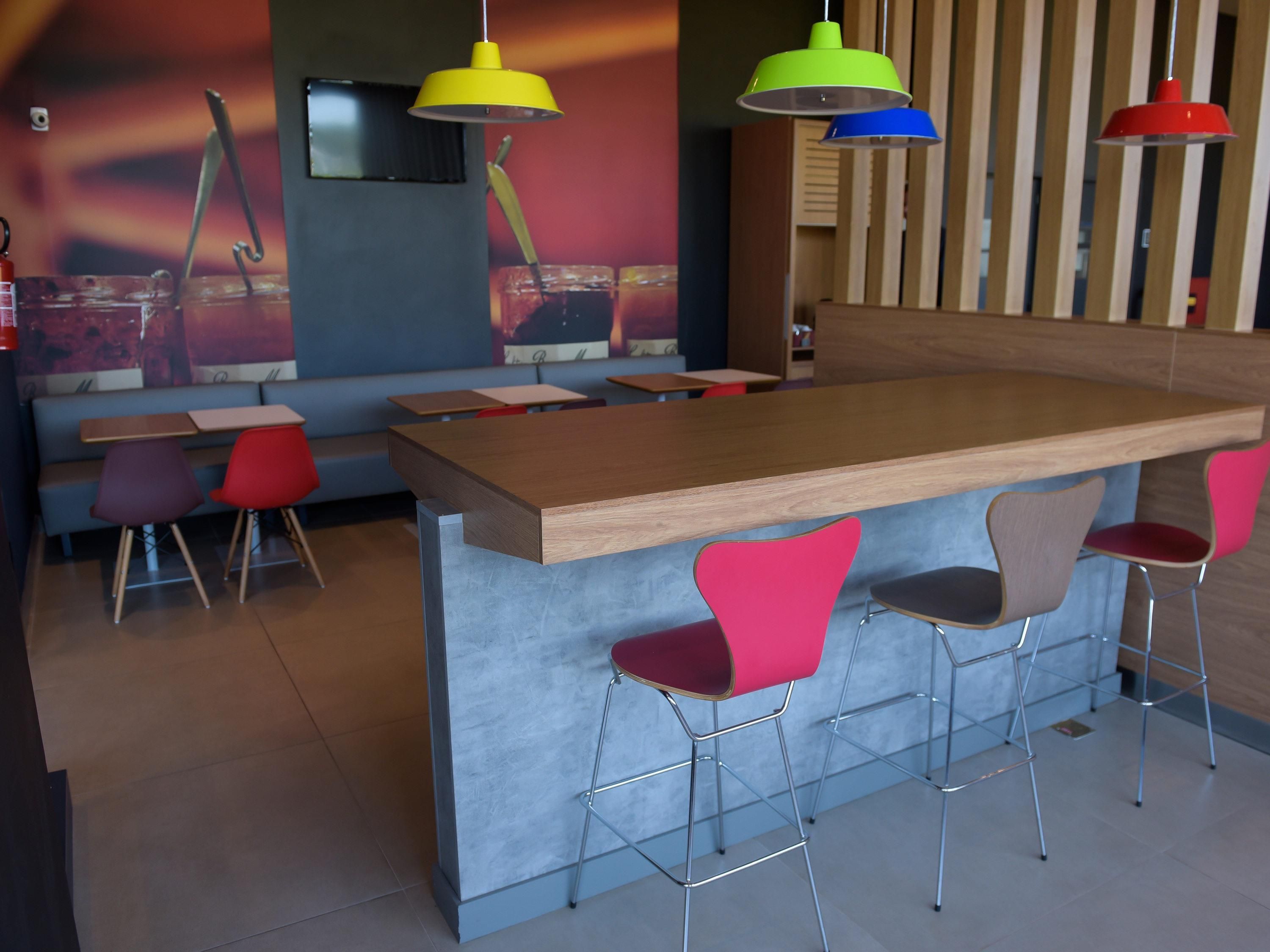 Una zona de bar con mostrador de madera y sillas de metal.