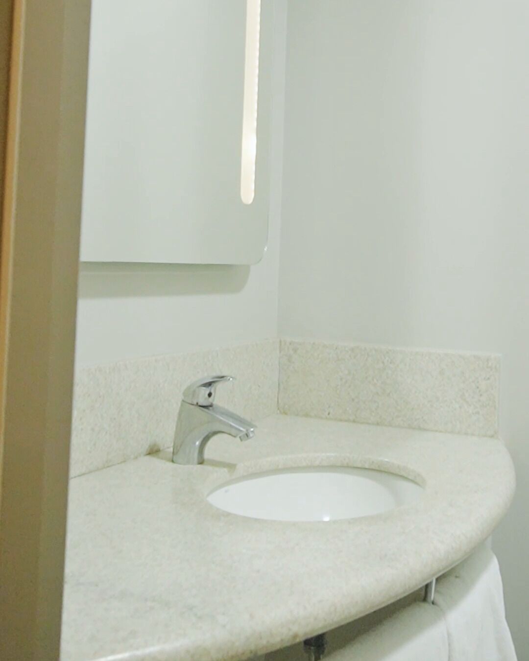 Un baño con un lavamanos blanco, un espejo y un grifo.