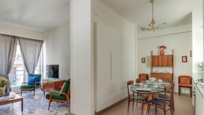A modern living room with a dining area, a TV, and a ceiling fan. - Apartments Florence - Santa Maria Balcony (Firenze)