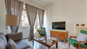 A living room with a sofa, a coffee table, a TV, a cabinet, and a window with curtains. - Apartments Florence - Santa Maria Balcony (Firenze)