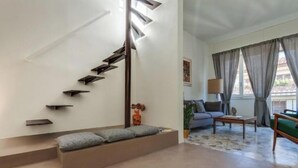A modern interior with a staircase, a sofa, a coffee table, and a lamp. - Apartments Florence - Santa Maria Balcony (Firenze)