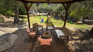 Una terraza de madera al aire libre con asientos y un columpio de fondo.
