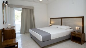 Un dormitorio con cama, mesitas de noche, ventilador de techo, ventana con cortinas y una silla de madera.