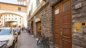 Una calle con coches estacionados, una bicicleta y un edificio de fachada de piedra y puertas de madera.