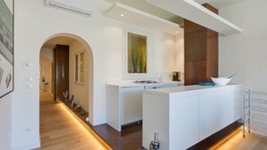 Una cocina moderna con una isla central, armarios blancos y una pared de acento de madera.