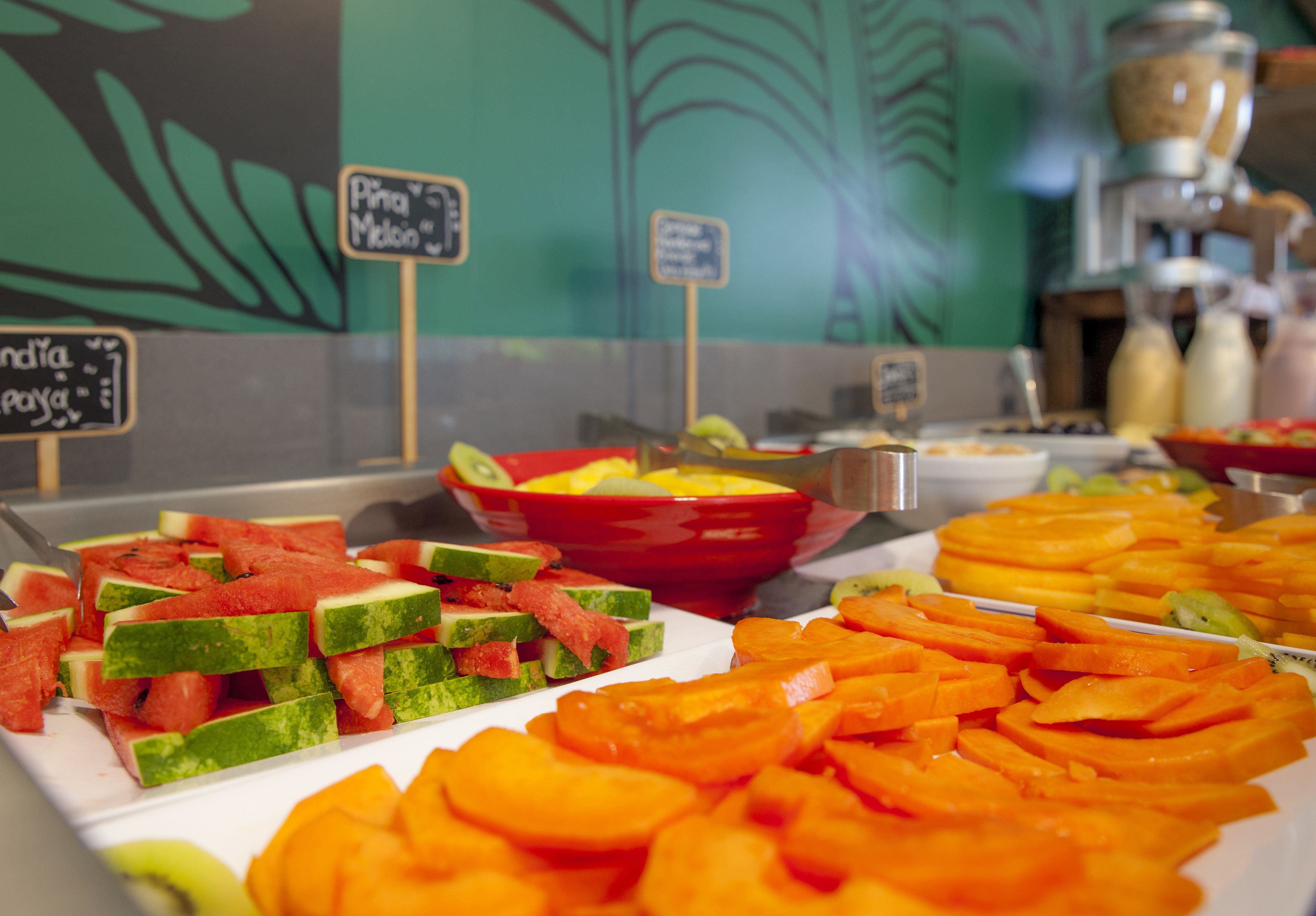 A buffet with various fruits and a coffee machine in the background.
