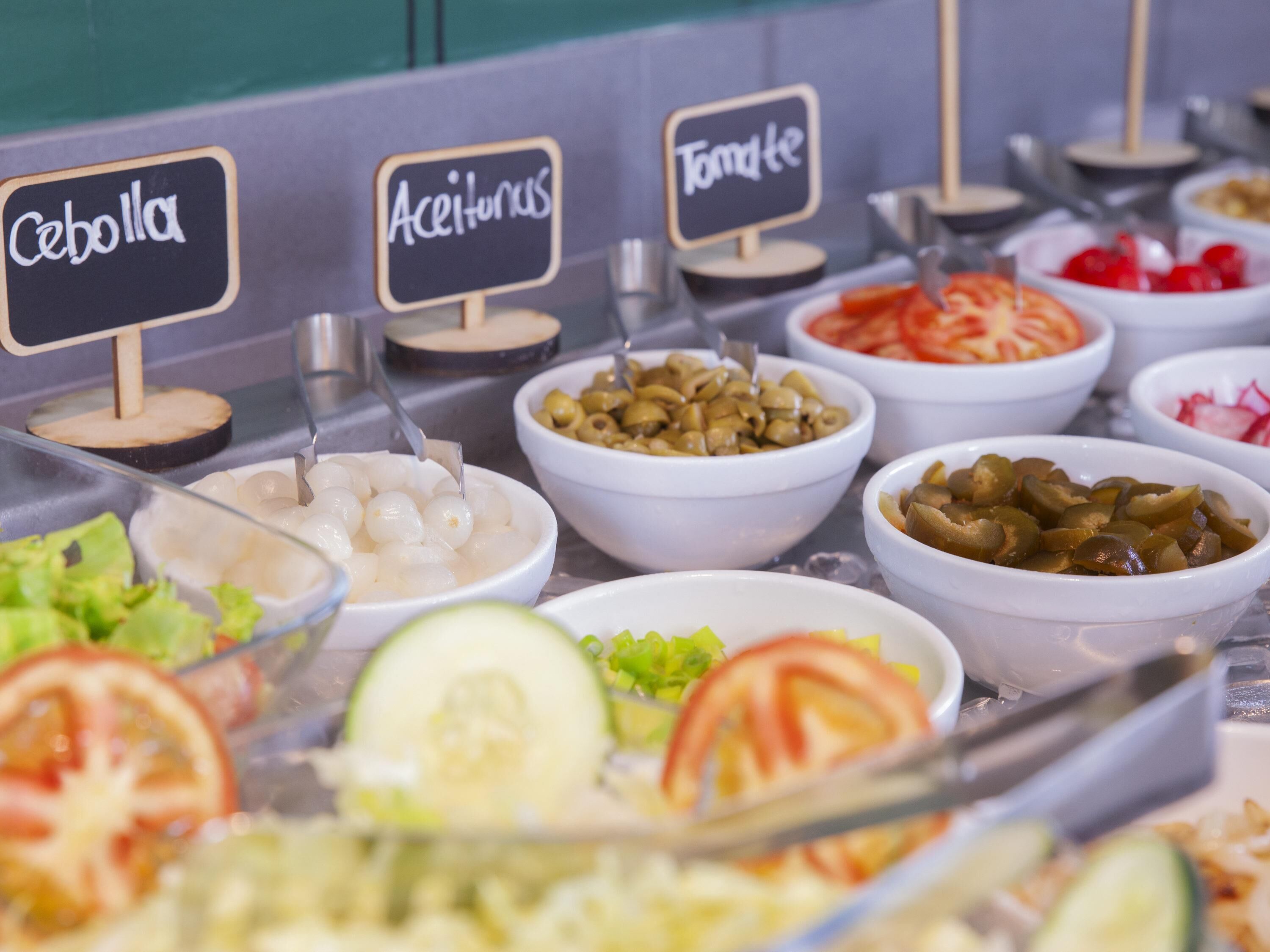 Un bufé con secciones identificadas para distintos tipos de comida.