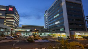 A modern hotel with multiple floors, a parking lot, and a visible entrance. - ibis Apartado (Apartadó)