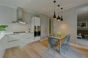 Une cuisine moderne avec une table à manger en verre, deux chaises, une cuisinière et un four encastré.