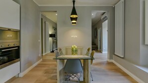 A modern kitchen with a glass dining table, a black pendant light, and a built-in oven.