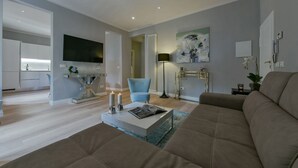 A modern living room with a sofa, a coffee table, a TV, and a painting on the wall.