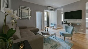 A modern living room with a sofa, coffee table, and TV. There are decorative items and a plant.