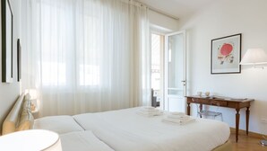 Ett hotellrum med en säng, ett skrivbord, en stol, en lampa och en inramad tavla på väggen.