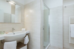 Une salle de bain moderne avec une douche à parois de verre, un lavabo et un miroir.