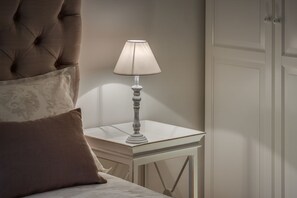 Ein Bett mit einer gesteppten Kopfteil, ein Nachttisch mit Lampe und ein Kleiderschrank.