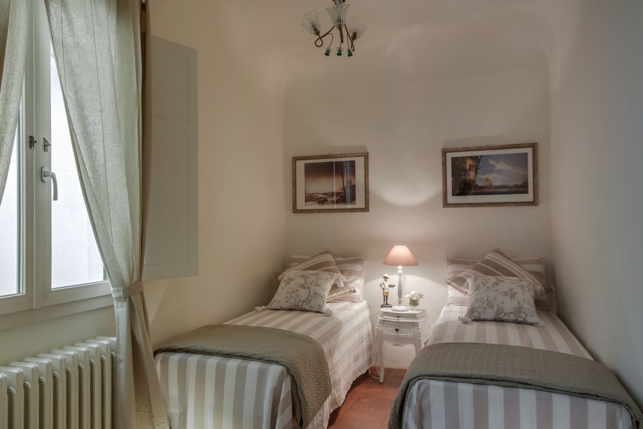 Un dormitorio con dos camas, una mesita de noche, una lámpara y dos cuadros en la pared.