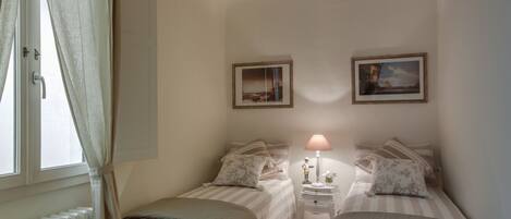 Ein Schlafzimmer mit zwei Betten, einem Nachttisch, einer Lampe und zwei gerahmten Bildern an der Wand.