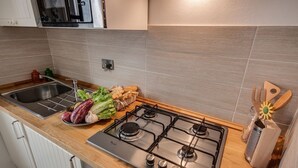 Une cuisine moderne équipée d’une cuisinière en acier inoxydable, d’un évier et d’un plan de travail en bois.