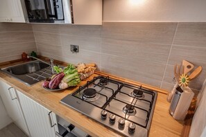 A modern kitchen with a stainless steel stove, a sink, and a wooden countertop.
