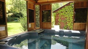 A hot tub with a view of a garden and a wooden structure. - Beau Vallon - Gîte et Chambres d'Hôtes (Sahorre)